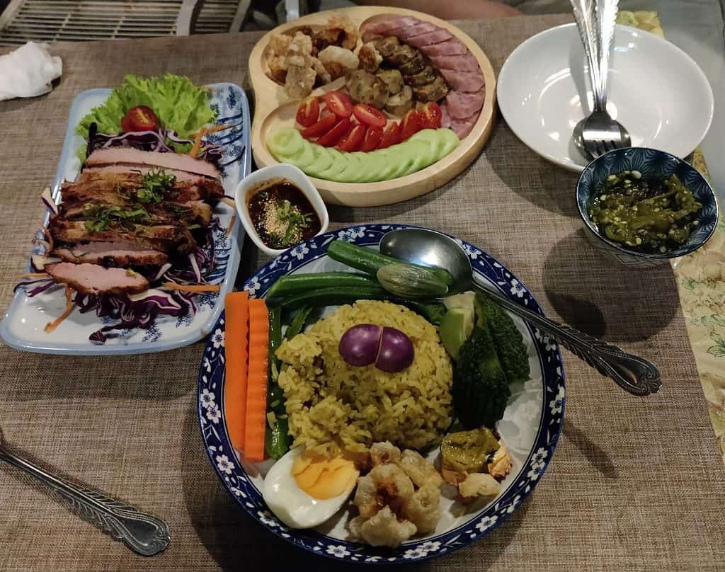Food dishes served at a house bar in Bangkok. Includes pork neck on the left, a fried rice at the bottom, and sausages, including a fermented sausage at the top.