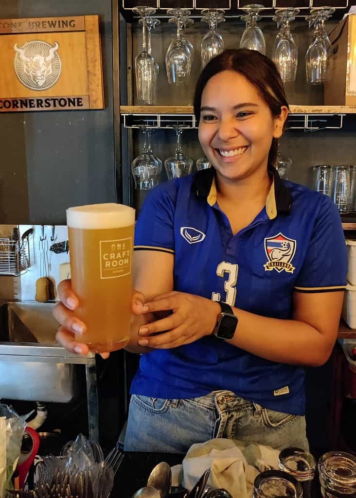 Craft Room Sathorn - craft beer bar in Bangkok Thailand. Waitress giving a big smile serving a fresh local Thai craft beer. 