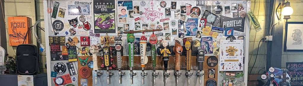 The tap wall at in Bangkok Thailand. Includes lots of stickers of breweries and other craft beers.