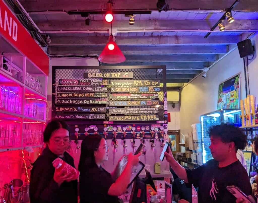 Inside the Highland Cafe, bar & Dispensary in Bangkok Thailand. 12 taps of craft beer behind the staff and customer.
